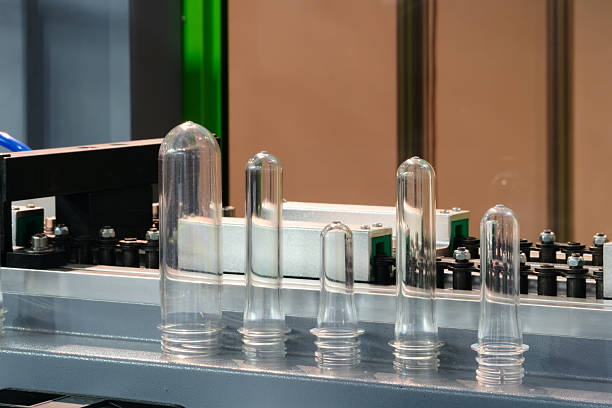 istock Industrial PET plastic bottle production machine, plastic preforms are on the machine. Industrial concept background 2253258971