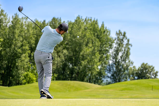 istock Caucasian Golfer in Striped Shirt Swinging with Intensity on Course 2253260470