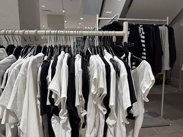 istock Minimalist black and white basic t shirts hang neatly on a rack inside a modern clothing store 2253260881