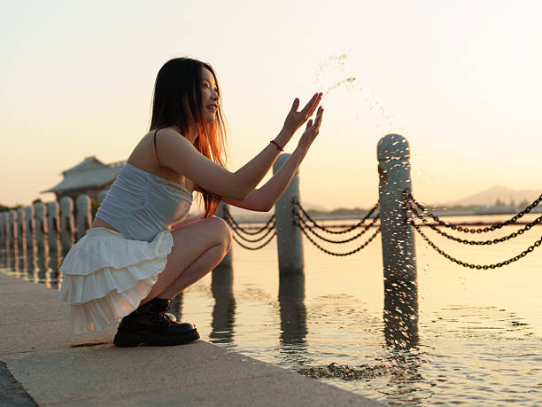 A woman playing by the water in the evening.