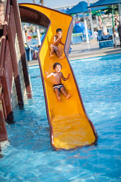 istock Young boys are enjoying a fun summer day, sliding down a water slide into a refreshing swimming pool at a water park. 2253262767