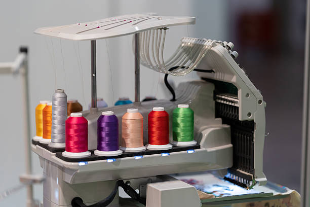 Multi-colored spools of thread are connected to an embroidery machine. Mid shot