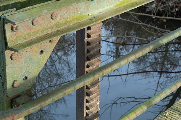 Rusted industrial gear mechanism showing decay and weathering over reflecting water