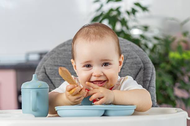 istock Laughing baby playing with food and spoon at mealtime. Complementary feeding 2253267953
