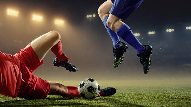 istock Explosive ground tackle with professional players fighting for ball on pitch 2253268307