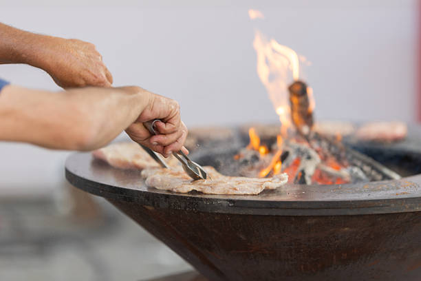 The chef cooks meat on the stove with a fire. Mid shot