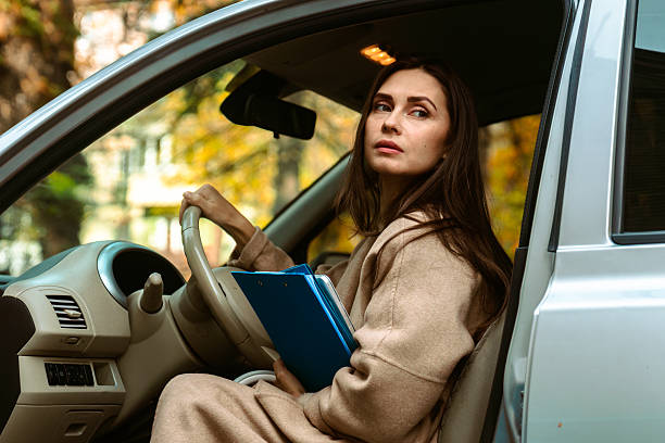 istock Woman Sitting in Car Holding Blue Folder 2253270563