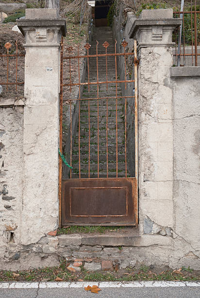 istock Rusty iron gate with stone pillars and stairway behind 2253271006