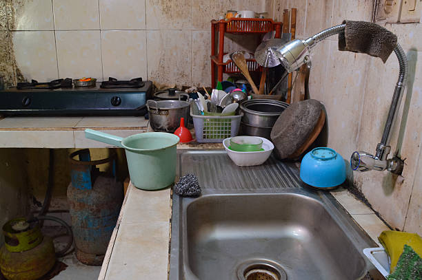 Messy kitchen counter, dirty plates and leftovers, cutting board, kitchen and fruits peels, unhygienic and stained crockery. Time to wash and clean up
