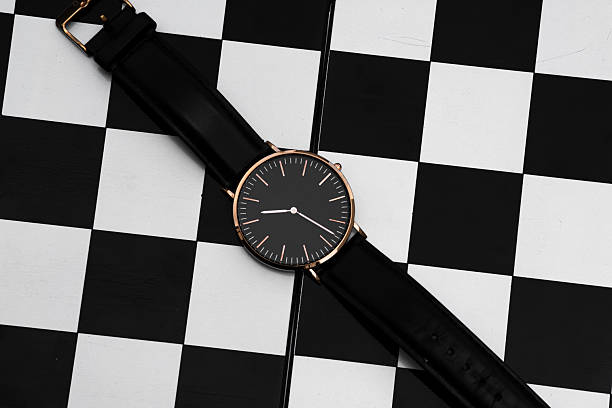Minimal black wristwatch on checkered background flat lay