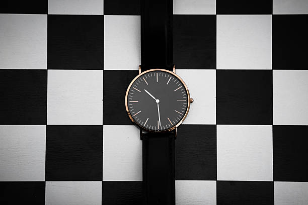 Minimal black wristwatch on checkered background flat lay