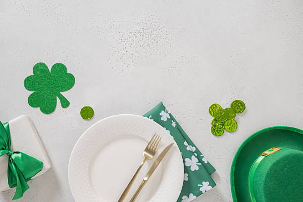 istock St Patricks Day table setting with white plate and clover leaves on green. 2253275581