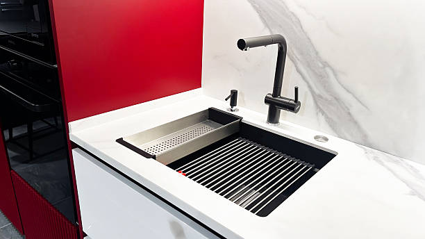 istock Modern kitchen interior with sleek black faucet, white marble counter, and vibrant red cabinets 2253276986