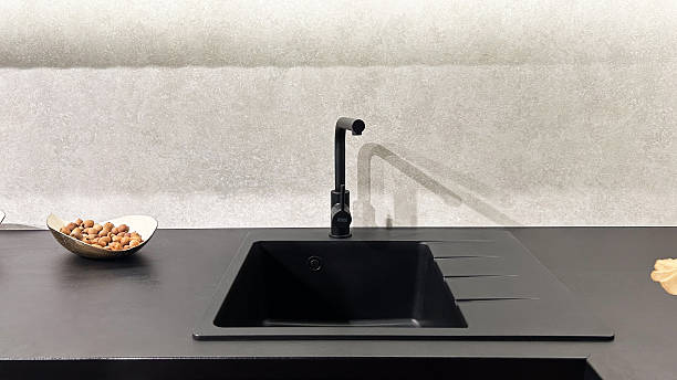 istock Modern black kitchen sink, faucet, dark countertop, nuts in bowl, grey wall background. 2253276994