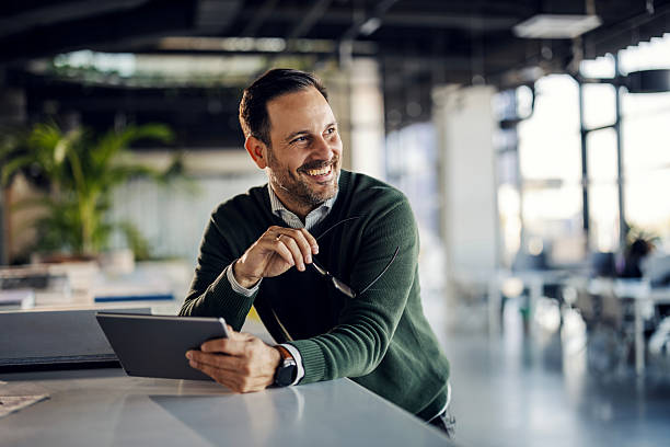 istock Happy businessman smiling holding digital tablet in modern office 2253278300