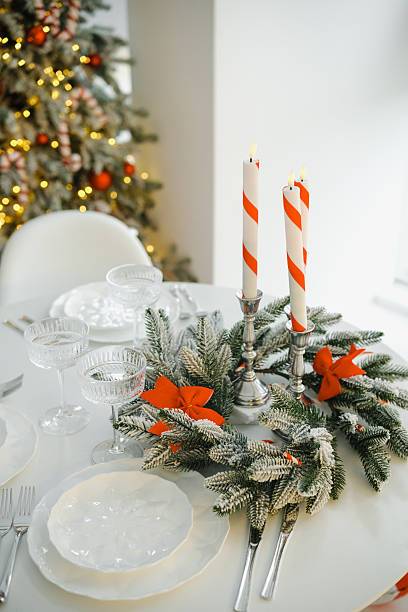 istock Festive holiday table setting with sparkling candles and green winter branches adorned with red bows. 2253278446