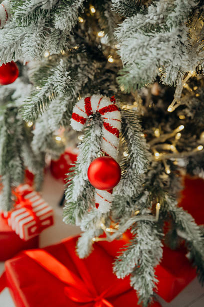 istock Decorated evergreen tree with white snow dusting, red baubles, candy canes and gifts below 2253278448