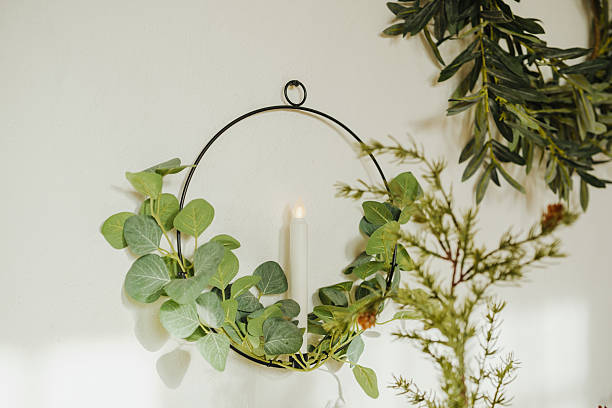 istock Circular greenery decor with lit candle inside, hanging on wall with soft light 2253278454