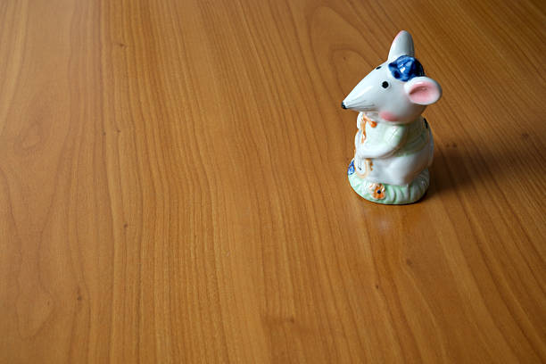 A delightful mouse figurine stands on a smooth wooden surface, radiating charm.