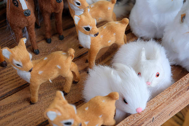 Delicate handmade animals rest together in a wooden crate under warm light.