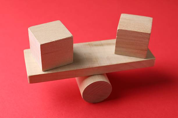 Risk. Wooden seesaw scale with cubes on red background, closeup