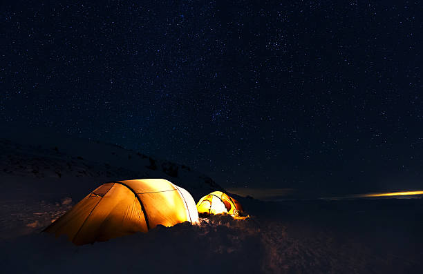 istock Illuminated camping tents on snowy mountain under starry night sky 2253285052