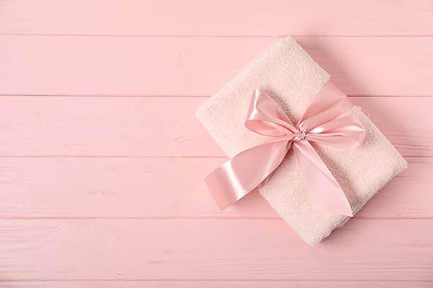istock Fresh terry towel with bow on pink wooden background, top view. Space for text 2253287713