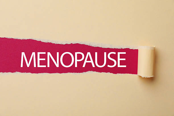 istock Word Menopause on crimson background, view through hole in torn beige paper 2253288910