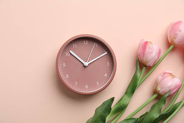 istock Menopause. Alarm clock and tulips on beige background, flat lay 2253288934