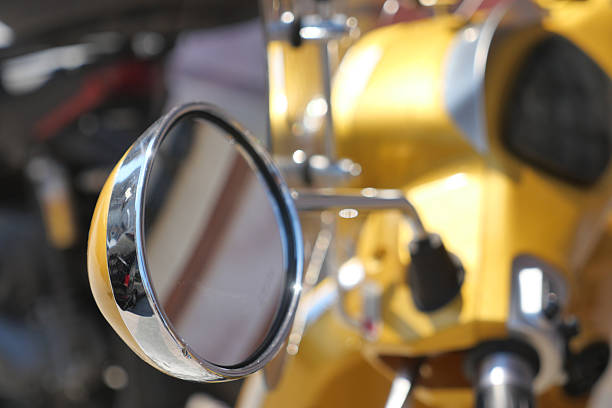 Close-up of a shiny motorcycle mirror reflecting the environment.