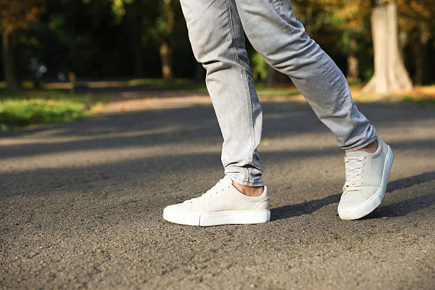 istock Man in stylish sneakers walking on asphalt outdoors, closeup. Space for text 2253292175