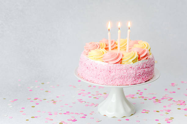 istock Birthday cake decorated with pastel icing and candles on a festive table 2253293566