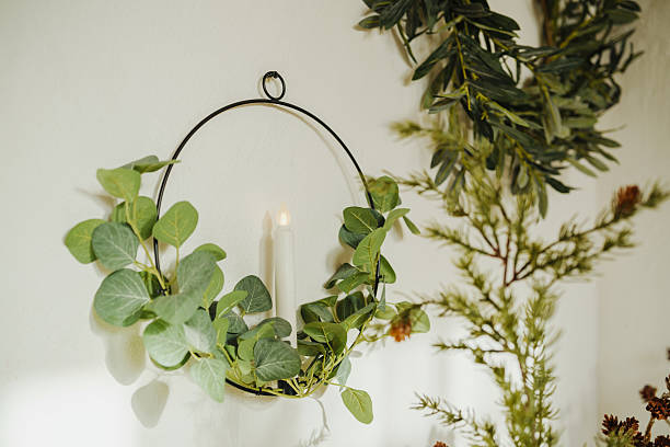 istock A simple candle glows within a green leafy circular wall decor against a plain background with foliage 2253293972