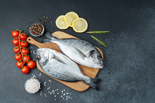 istock Raw dorado fish tomatoes lemon and spices on cutting board 2253294024