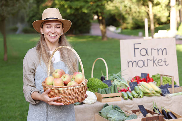 Farmer with apples in wicker basket near stall at market