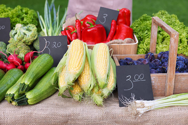 Many different vegetables and plums on stall at farmer's market, closeup