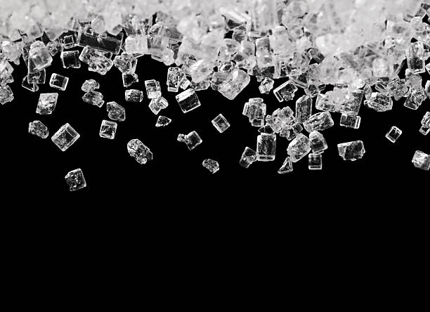istock Macro shot of falling sugar crystals isolated on black background. 2253300681