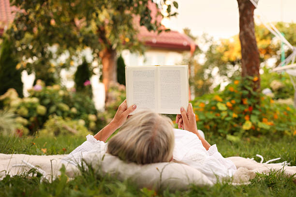 istock Senior woman reading book on blanket in garden 2253300721