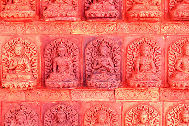 A bas-relief with multiple Buddha figures in Nanshan Park, Sanya, Hainan. The stone wall is painted in warm terracotta tones, illuminated by the bright afternoon sun.
