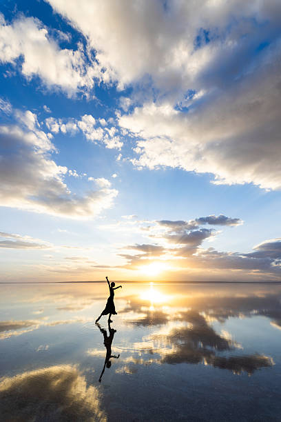 istock Silhouette of a dancer at sunset reflected on calm water 2253301219