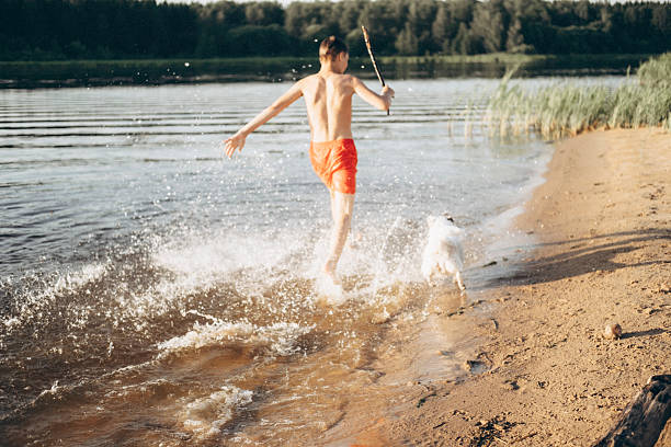 istock Boy Playing with Dog in Water at Lakeside Beach 2253302236
