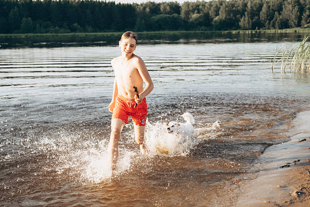 istock Boy Playing with Dog in Water at Lakeside Beach 2253302239