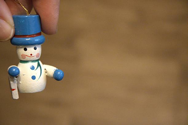 Snowman shaped Christmas ornament held in hand, close-up view. Winter holiday decoration with Copy Space.