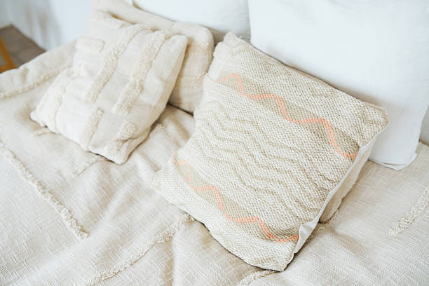 Soft neutral fabric pillows on a textured blanket cozy bedroom detail