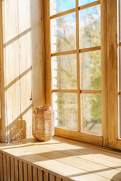 istock Natural light shines through a wooden window onto a woven lantern on a rustic sill. 2253302993