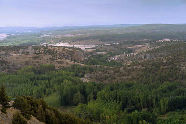 Wide panoramic view of the lobos river canyon near vinuesa, soria, spain, showing meandering river, forests, rolling hills, rural village and clear summer sky