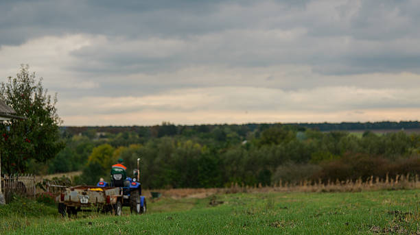 istock Farmer driving a tractor with a trailer through a field on a cloudy day 2253304979