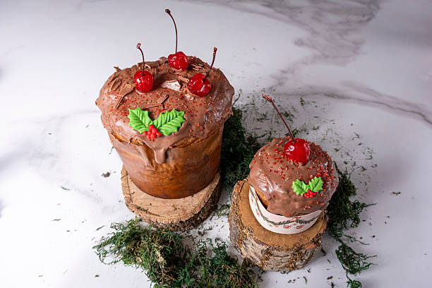 Panettone with melted chocolate frosting and cherries alongside moss.