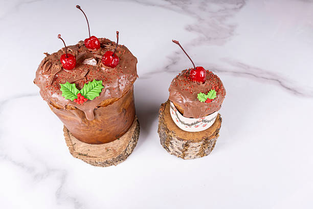 Panettone with a melted chocolate coating and cherries on a piece of tree trunk.