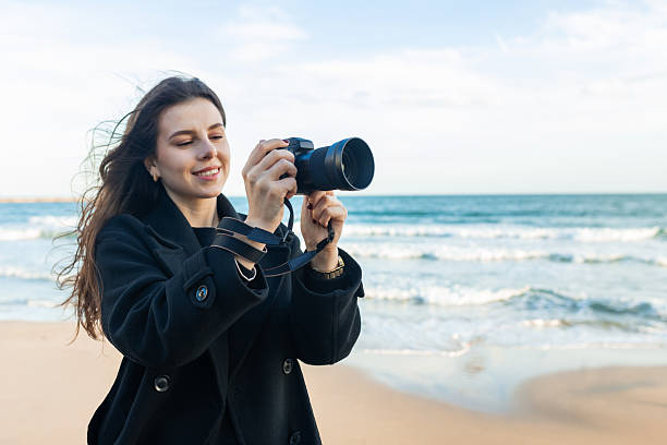 istock Smiling female photographer holding a camera on a 2253307112